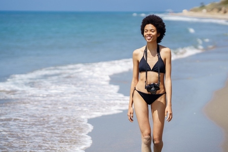 Black woman with photo camera on beach