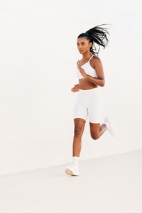 Fit female in white fitness attire jogging outdoors  Full length of a young woman sprinting