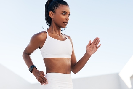 Close up of a young woman in a sports bra doing warming up exercises  Cropped of a professional fitness athlete exercising outdoors