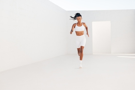Full length of a fitness woman in white sportswear  Slim female running in white outdoor studio