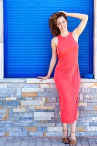 Stylish woman in red dress standing near blue shutters