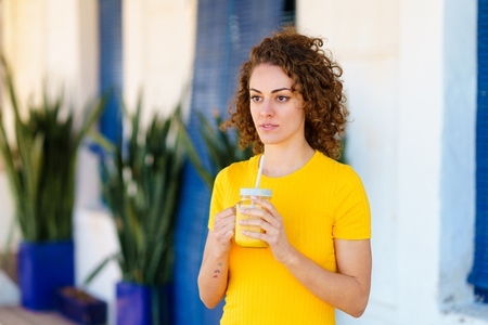 Pensive woman with juice in glass jar looking away