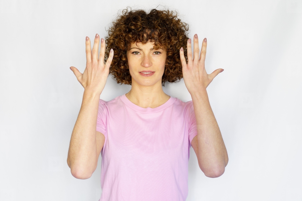 Adult woman with curly hair showing hands in studio