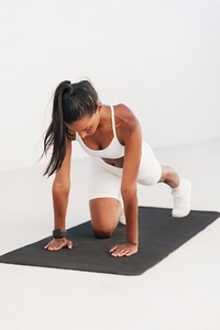 Slim female exercising on a mat  Full length of a young athlete warming up on a black mat