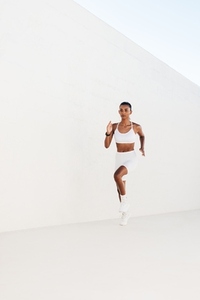 Slim female sprinter running outdoors  Full length of young sportswoman jogging