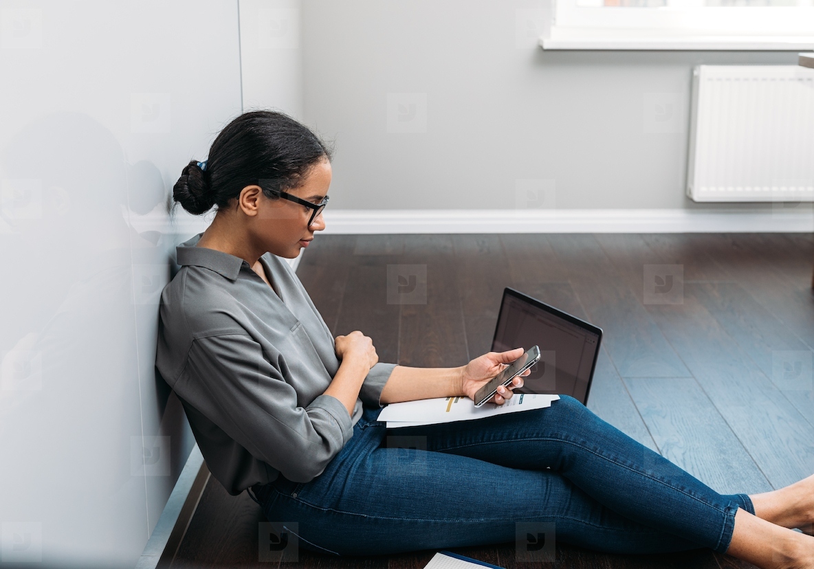 Side view of a young woman counting bills while sitting on a floor at home