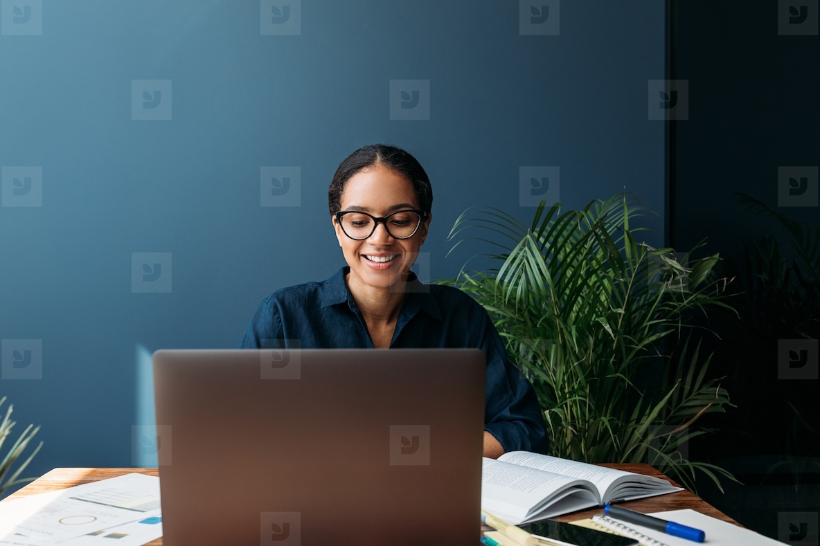Cheerful woman in eyeglasses at the table working on laptop at home