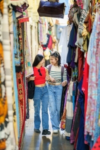 Two Chinese women tourists shopping clothes in street bazaar