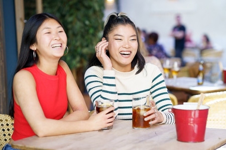 Cheerful Asian women resting in cafe with drinks