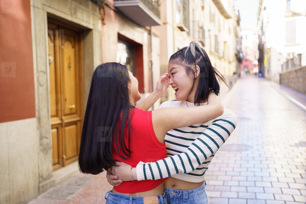 Happy Asian women hugging on street