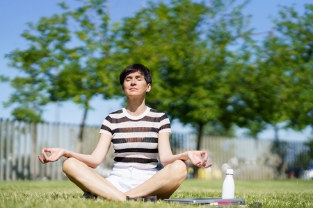 Calm woman meditating in park with closed eyes