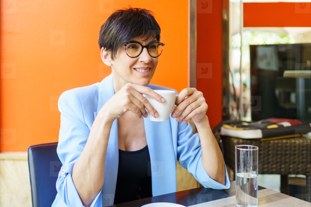 Cheerful elegant woman drinking coffee in cafe