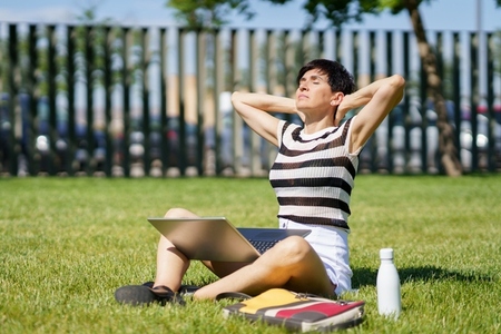 Calm adult woman stretching neck during work on laptop