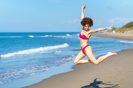 Active female jumping on sandy seashore