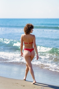 Calm woman walking on sandy seashore during summer vacation