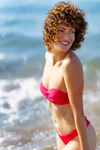 Graceful happy lady standing on seashore and smiling