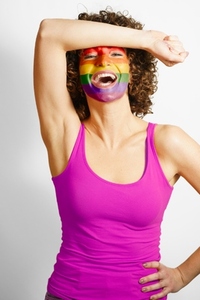 Happy woman with face painted in LGBT colors laughing in studio