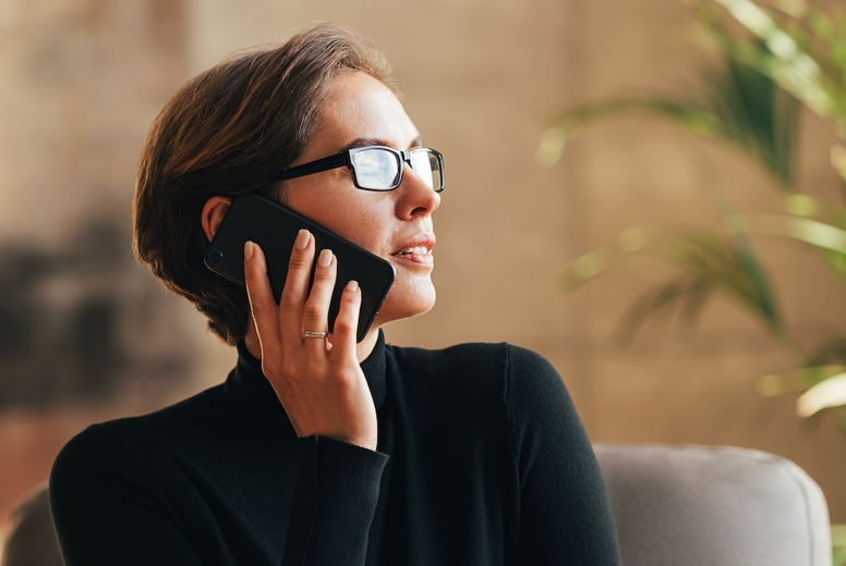 Businesswoman in eyeglasses wearing black formal clothes talking on mobile phone