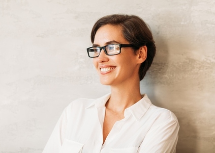Cheerful businesswoman wearing eyeglasses  Portrait of a smiling entrepreneur leaning against a wall wearing formal wear