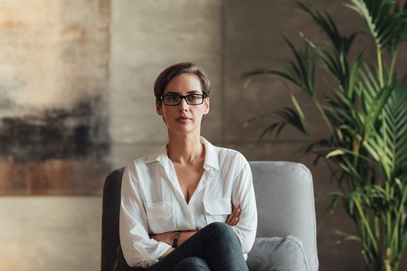 Confident female sitting in her loft  Businesswoman in eyeglasses and formal wear
