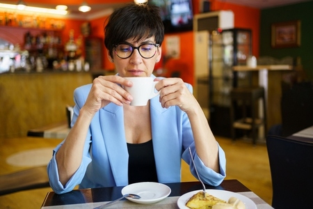 Calm middle aged woman enjoying hot coffee in cafe