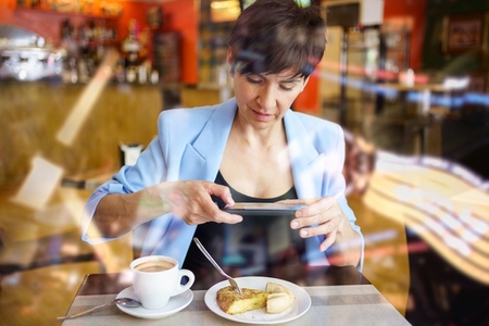 Young woman taking photo of dish with smartphone