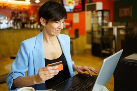 Focused woman making online payment using laptop in cafe