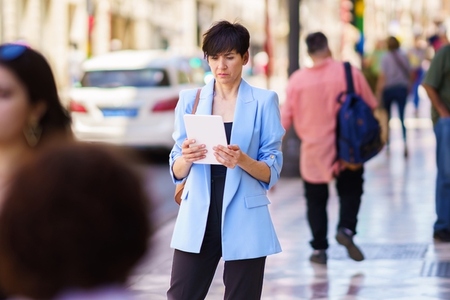 Focused woman with tablet on street