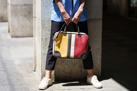 Faceless woman with colorful handbag on street