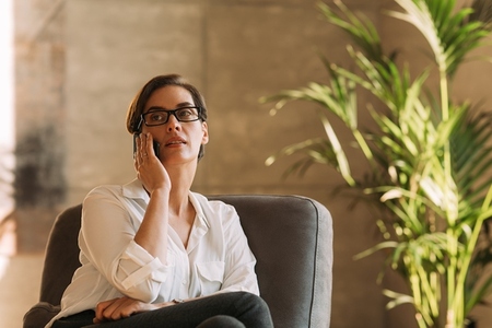 Middle aged businesswoman in eyeglasses talking on mobile phone