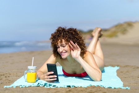 Smiling woman chatting on mobile phone on beach