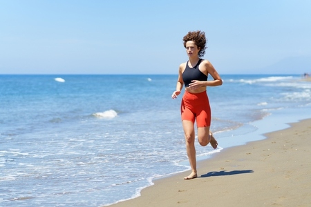 Focused young woman exercising on beach near water
