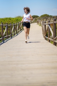 Active sportswoman jogging on boardwalk in countryside