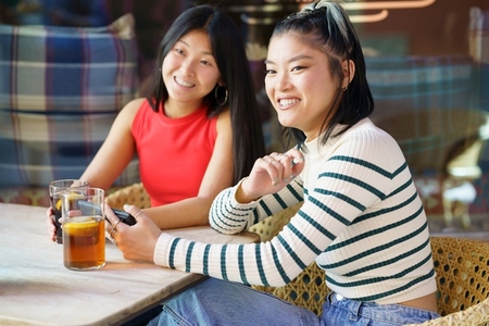 Two young Chinese women having a drink on the terrace of a typical bar in Granada