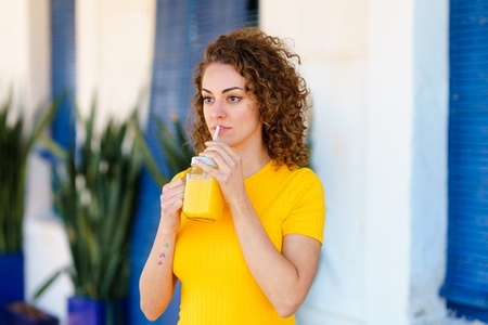 Thoughtful woman drinking orange juice on street