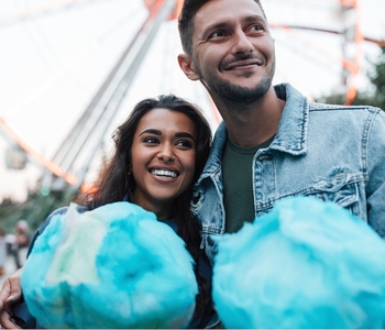 Young happy couple standing together holding blue cotton candy