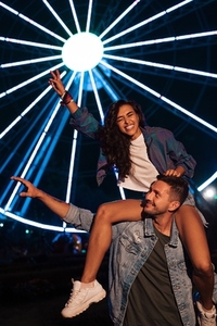 Happy couple having fun at night against lights of ferris wheel