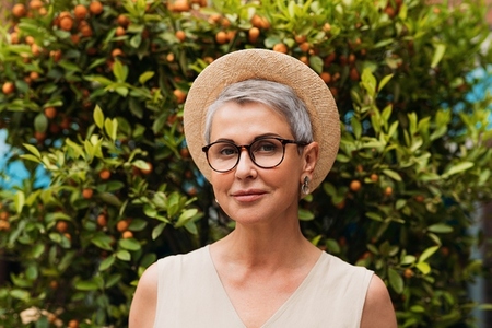 Portrait of a stylish mature woman  Senior female with gray hair wearing glasses and a small straw hat