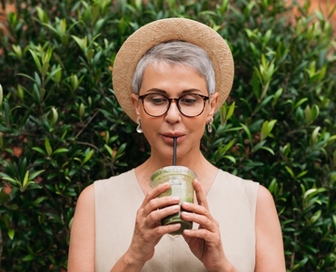 Aged woman with short hair drinking a smoothie  Senior female enjoying cocktail outdoors