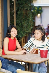 Positive Asian women talking in cafe together