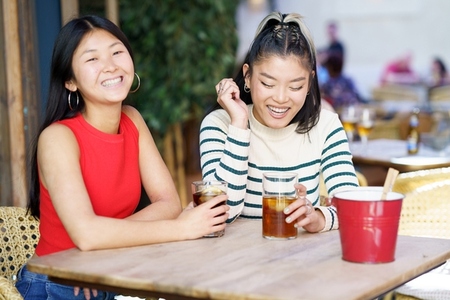 Two young Chinese girls having a drink on the terrace of a typical bar in Granada