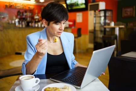 Focused young woman using laptop in cafe