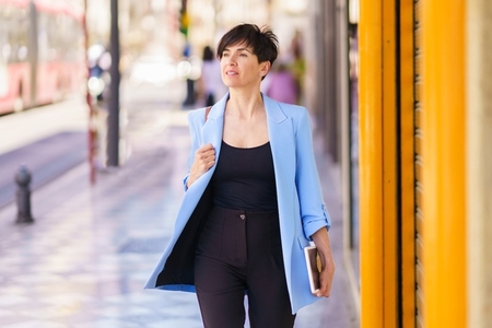 Stylish woman in smart formal clothes walking on street