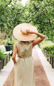 Rear view of a female with a big straw hat standing in the park