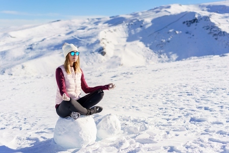 Cheerful woman sitting with lotus pose on snow
