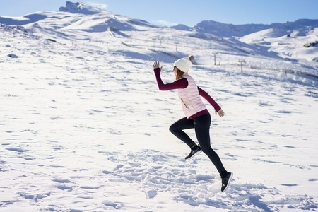 Excited young woman running on snowy plain