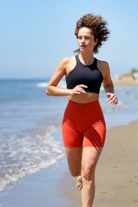 Happy young woman enjoying running exercise on beach