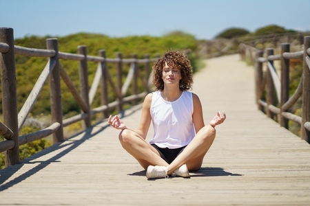 Young woman meditating on wooden pier