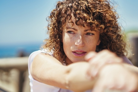 Young woman with curly hair and freckles on face