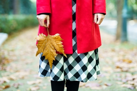 Woman in outerwear standing with maple leaf